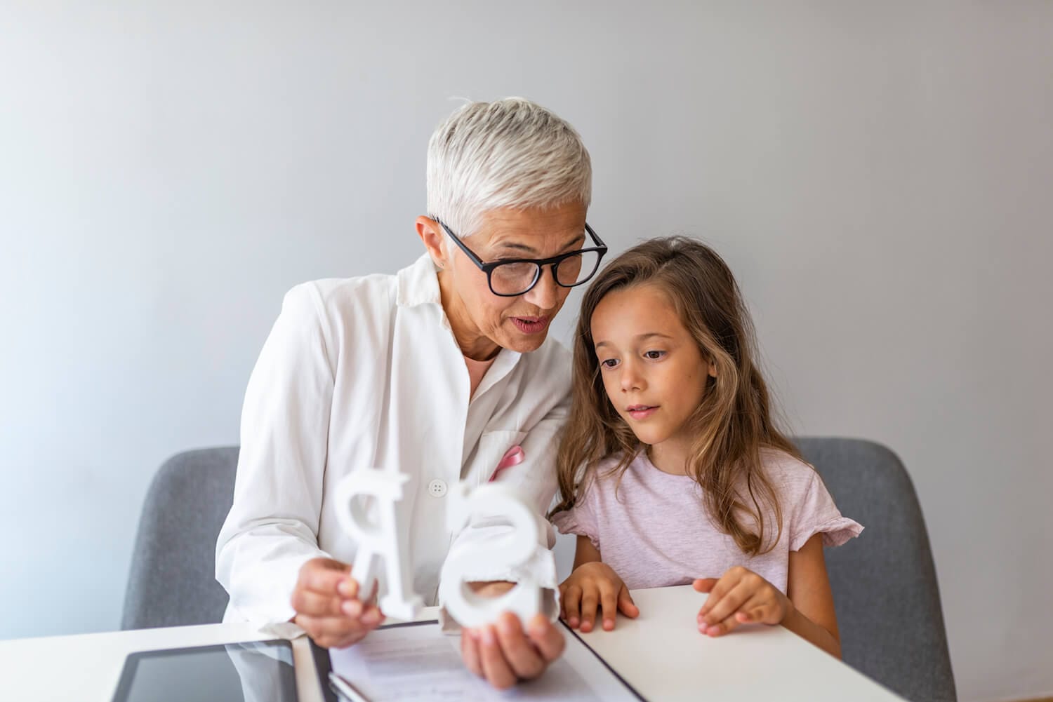 Orthophoniste guidant une enfant : apprentissage des sons et rééducation du langage.